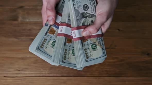 Male Hands Flipping Stacks 10000 Dollar Bills on Wooden Background Slow Motion