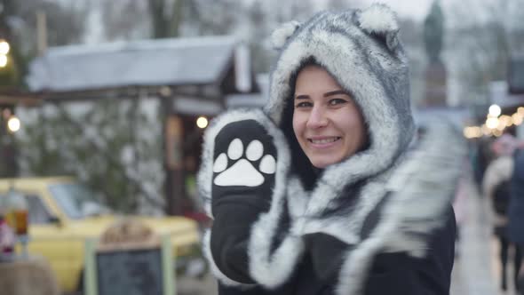 Funny Caucasian Girl in Fur Animal Hat and Gloves Looking at Camera and Smiling, Young Cheerful