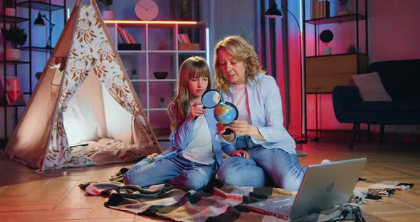 mother sitting on the bedcovers on the floor together with her smart interested daughter