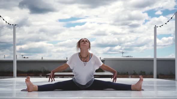 Young Woman Is Practicing Yoga, Sitting in Wide-Angle Forward Bend Pose