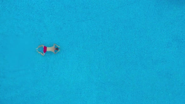 Aerial View of Man in Red Shorts Swims in the Pool. Slow Motion