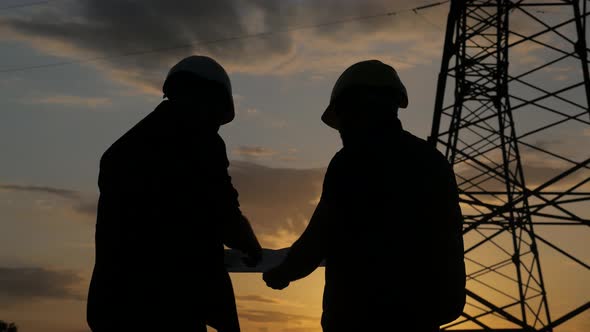 Silhouette of Engineers Looks at the Construction of High-voltage Power. Teams Engineer Looking