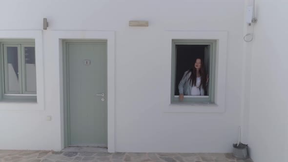 Aerial view of woman opening window in traditional white houses, Greece.