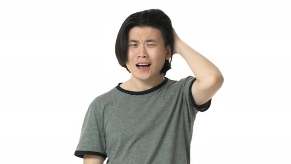 Portrait of Tense Chinese Man in Casual Gray Tshirt Scratching His Head While Being Nervous or