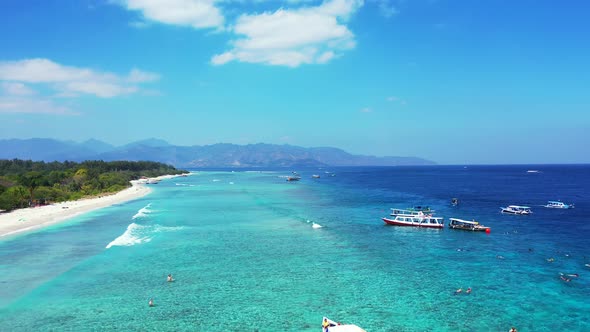 Wide flying travel shot of a white paradise beach and aqua blue water background in colorful