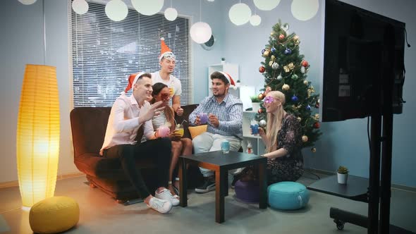 Young People in Santa Hats and Party Masks Making Cheers on Christmas