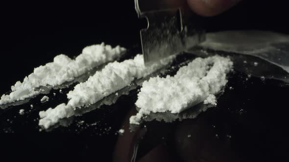 Lines of cocaine being cut with razor blade on table top