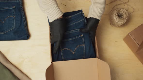 Man Warehouse Worker in a Post Room Packing Clothes Orders for Distribution Top View of Hands Pack