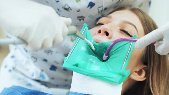 The dentist using the device rinses the tooth with water during the tooth treatment procedure.