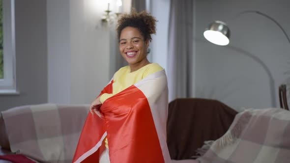 Middle Shot Portrait of Smiling African American Woman Wrapping in Canadian Flag Looking at Camera