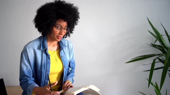 Positive black female talking with person and taking notes in notebook