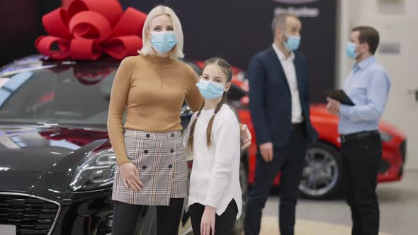 Happy Caucasian Mother and Daughter in Covid19 Face Masks Posing in Dealership with Father