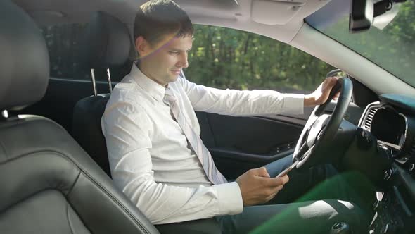 Smiling Bussinessman in Car Texting on Smartphone