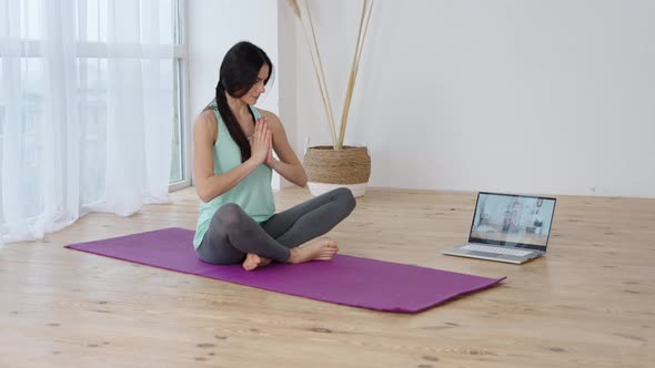 Young Woman Following Online Yoga Class on Laptop