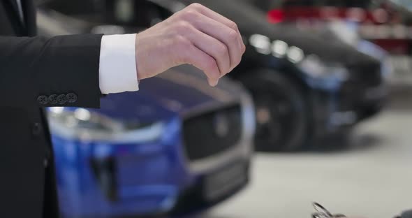 Close-up of Male Caucasian Hand Giving Car Keys To Customer and Shaking His Hand. Dealer and Client