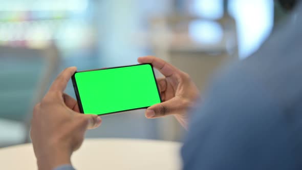 African Man Looking at Smartphone with Green Chroma Key Screen