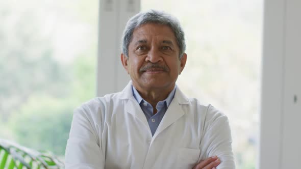 Portrait of african american male senior doctor with arms crossed smiling at home