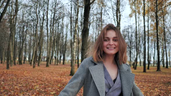 A Beautiful and Happy Girl is Walking in the Autumn Park