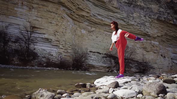 Girl Does Splits on Background Mountain River and Rocks