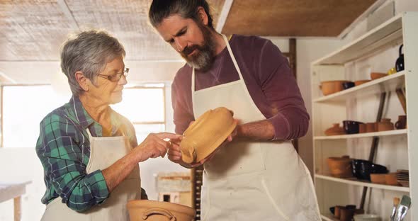 Male and female potter interacting while examining a pot