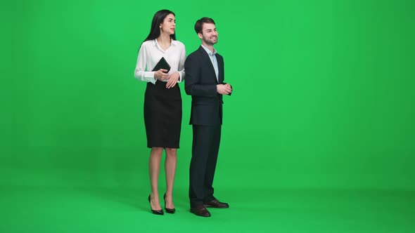 Man and Woman in Suits Stands in the Green Space of the Chromakey They Discuss Subjects While