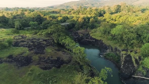 Drone footage of a single road, a small bridge and a river during a sunrise.