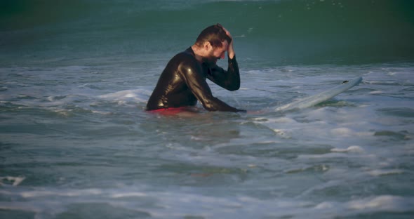 Portrait of a Handsome Senior Athlete in Age Sits on a Surf Board in the Water Waiting for a Wave to