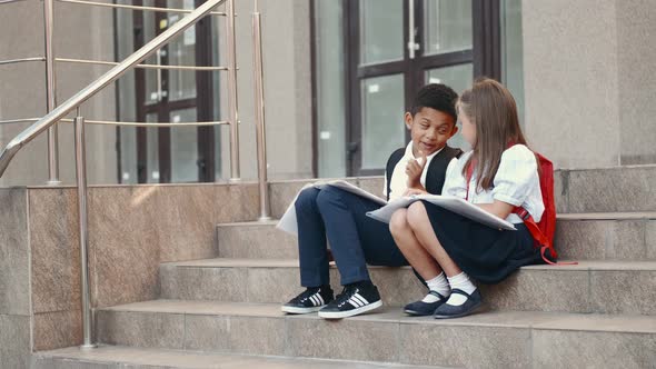 School Children Reading Book While Sitting on Stairs