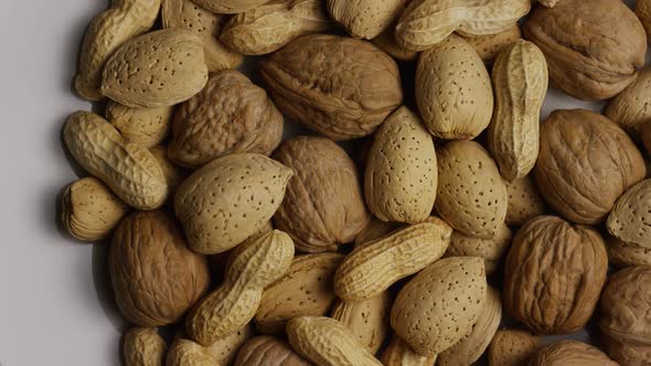 Cinematic, rotating shot of a variety of nuts on a white surface - NUTS MIXED