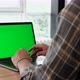 Close-up of a Man Uses Laptop with Green Mock-up Screen While Sitting at the Desk in His Cozy - VideoHive Item for Sale