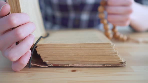 Close Up of a Rosary in the Hands of a Woman and the Open Bible