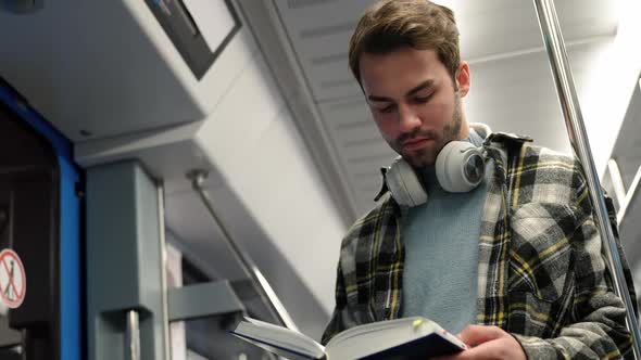 Handheld Young Guy Rides the Subway and Reads a Book a Student Goes to Study at the University