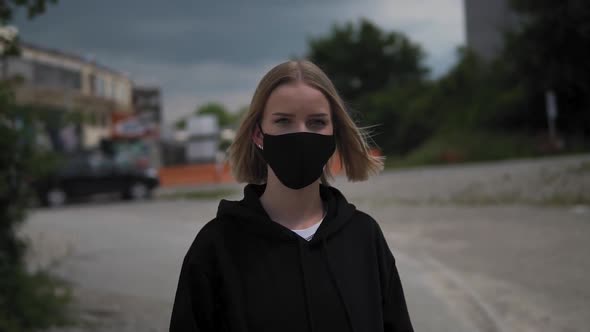 Portrait of a Young Blonde Female With Face Mask in Exterior Looking at Camera. Covid-19 Virus Pande