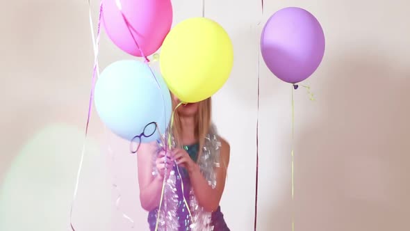 Slow motion of happy blonde woman jumping with balloons in photo booth