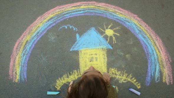 A Child Draws the Ukrainian Flag with Chalk on the Pavement