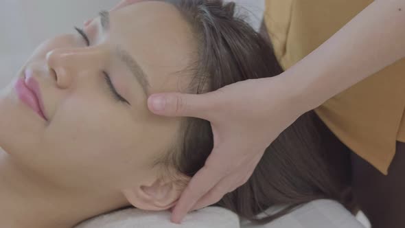 An young Asian woman lying down on a massage table in a spa at the resort during holiday.