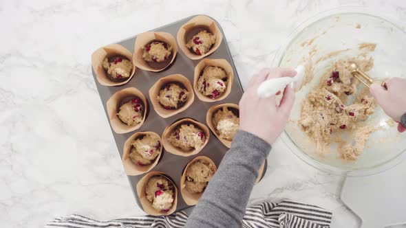 Flat lay. Step by step. Scooping dough into tulip muffin liners with mixture scoop to bake cranberry