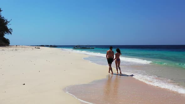 Boy and girl happy together on paradise tourist beach time by aqua blue lagoon with white sand backg