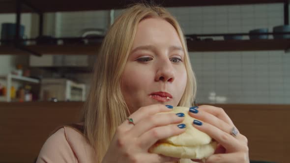 Portrait of Happy Woman Eating Tasty Hamburger at Cafe