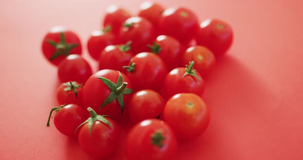 Video of close up of fresh red cherry tomatoes on pink background