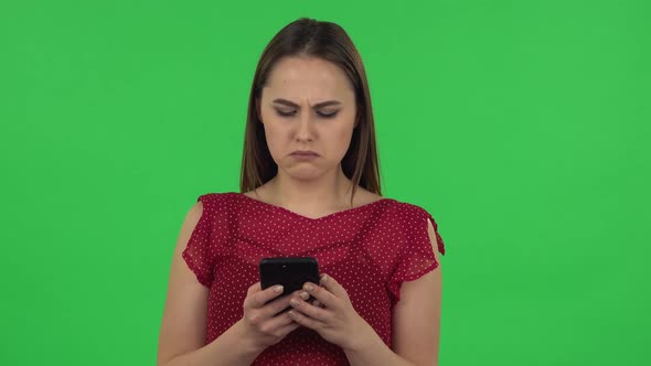 Portrait of Tender Girl in Red Dress Is Texting on Her Phone. Green Screen