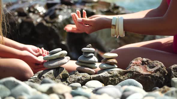 Woman Bilds Stones Pyramid on the Seashore on a Sunny Day on the Blue Sea Background