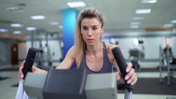 Young woman on bike at gym exercising