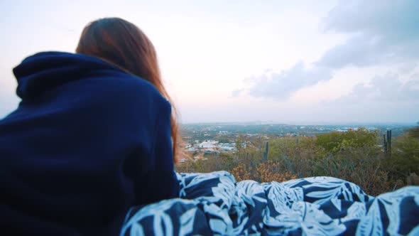 Girl laying on blanket watching sunrise from viewpoint, Over the Shoulder Push