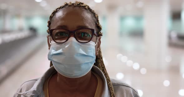 Mature african woman looking on camera while wearing safety face mask for coronavirus outbreak at ai