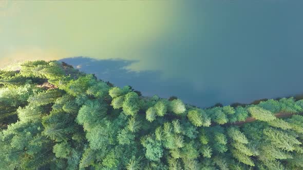 Top down aerial view of big lake with clear blue water between high mountain hills covered with