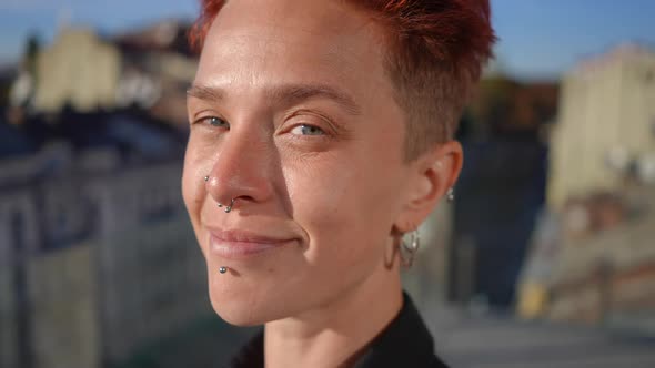 Headshot of Positive Pierced Adult Woman Looking at Camera Smiling in Sunshine