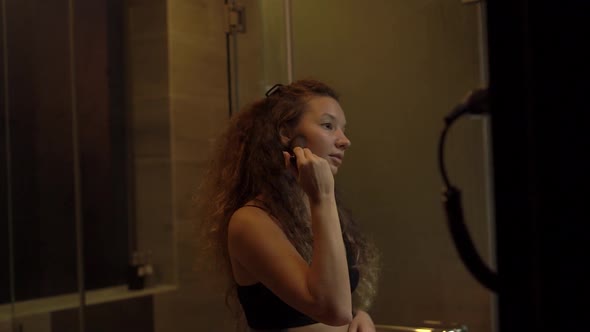 Concentrated Lady Applies Makeup Powder at Bathroom Mirror