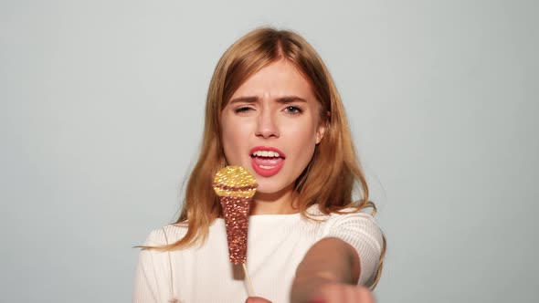 Young beautiful woman singing favorite songs with props fake microphone