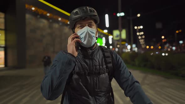 Male Delivery Man with Bicycle Wearing Helmet and Protective Mask From Covid Virus and Pollution